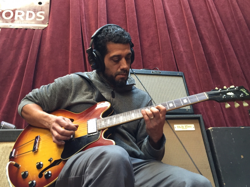 A photo of Babak Tondre playing guitar in the Wide Hive Studio.