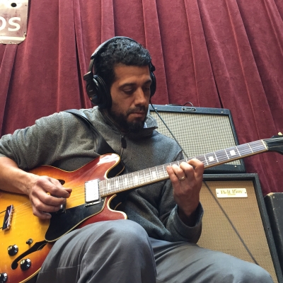 A photo of Babak Tondre playing guitar in the Wide Hive Studio.