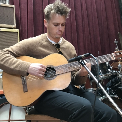 A photo of Ross Howe playing guitar at Wide Hive Records in Berkeley, California.