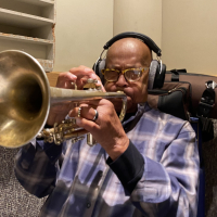 A photo of Eddie Henderson playing the trumpet with headphones on at Wide Hive Studios.